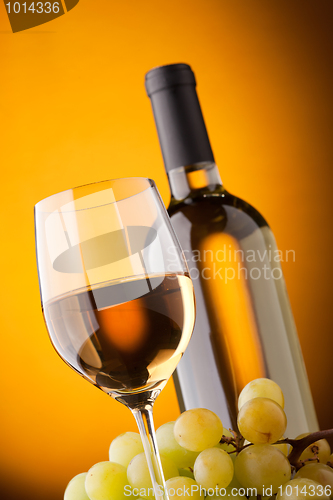 Image of Bottom view of a glass of white wine bottle and grapes 