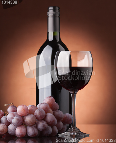 Image of A bottle of red wine, glass and grapes