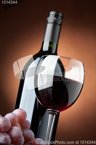 Image of A bottle of red wine and a wine glass closeup