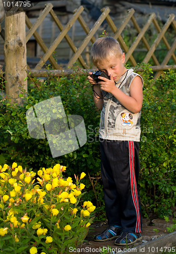 Image of The boy photographs flowers.