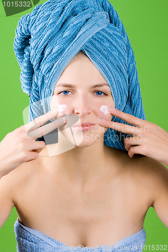 Image of young woman applying facial cream