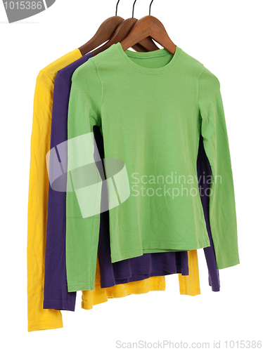 Image of Three long sleeved shirts on wooden hangers