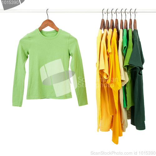 Image of Green and yellow shirts on wooden hangers