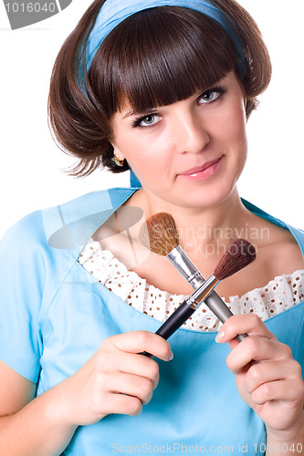 Image of woman in blue dress with two make-up brushes 