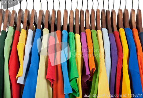 Image of Variety of multicolored clothes on wooden hangers