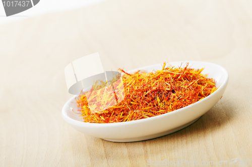 Image of Saffron leaves spice in saucer on wood