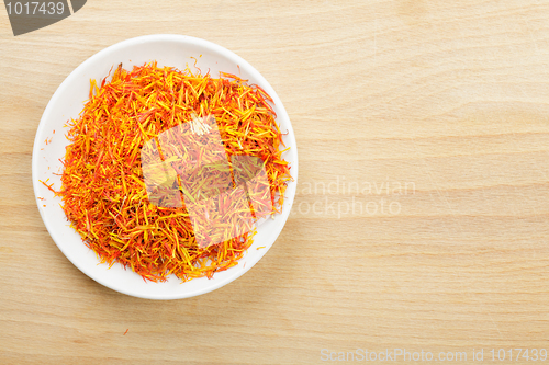 Image of Saffron leaves spice in saucer on wood above view