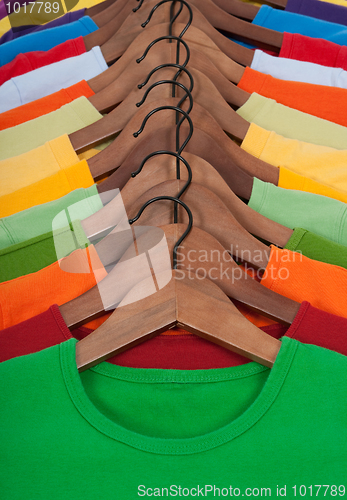 Image of Many vibrant t-shirts on wooden hangers