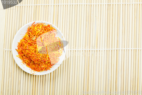 Image of Saffron leaves spice in saucer on mat above view