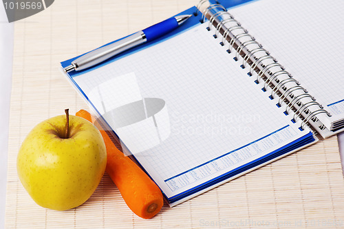 Image of Open notebook, yellow apple and pencil 