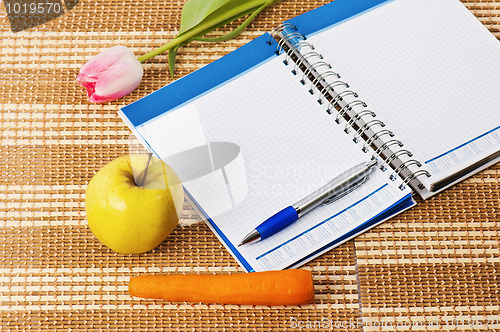 Image of Open notebook, yellow apple and pencil 