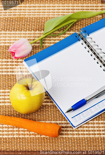 Image of Open notebook, yellow apple and pencil 
