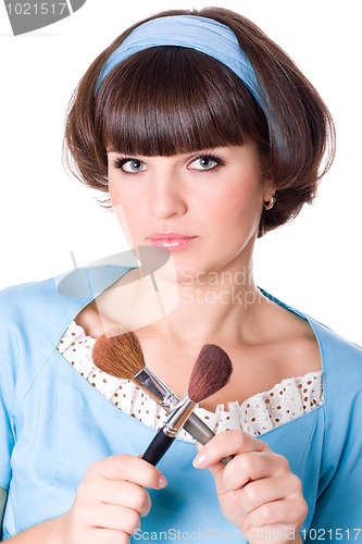 Image of woman in blue dress with two make-up brushes 