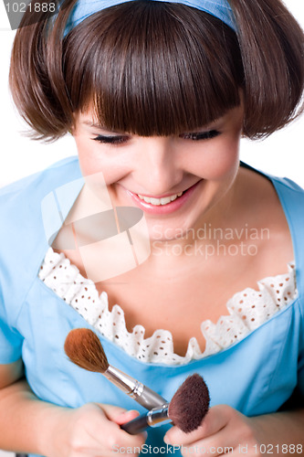 Image of woman in blue dress with two make-up brushe