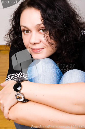 Image of brunet woman sitting on a wooden floor