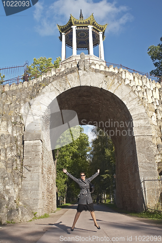 Image of young women jump under arch in the park