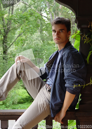 Image of Relaxed young man sitting at wood