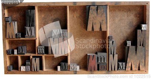 Image of letterpress M in wood and metal in a type case