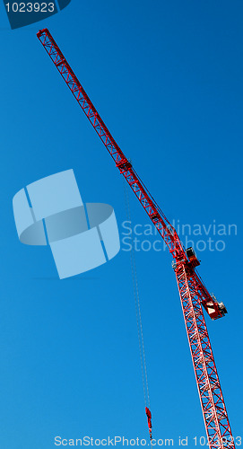 Image of red construction tower crane with blue sky