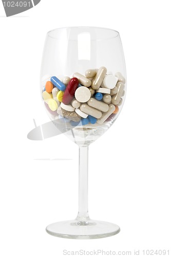Image of glass of multicolored tablets and capsules