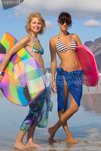 Image of two woman with  bodyboard on the beach 