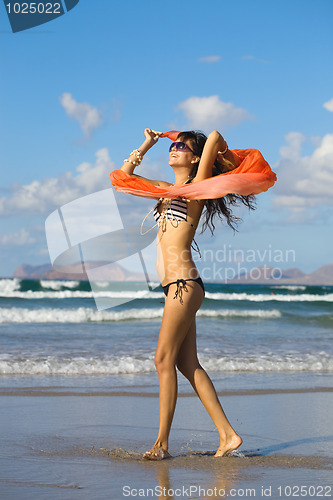 Image of young  woman dancing with kerchief against the blue sky