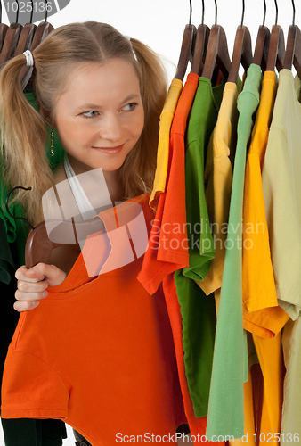 Image of Curious girl looking out of the clothes rack