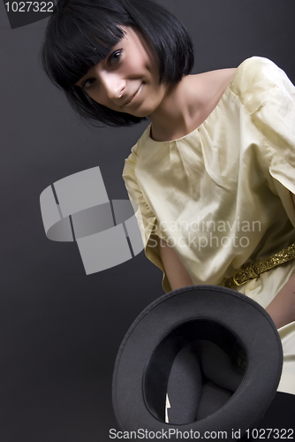 Image of Young brunette holding a hat    