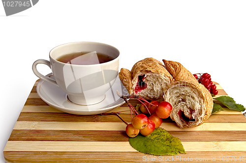 Image of White cup and a croissant on the board