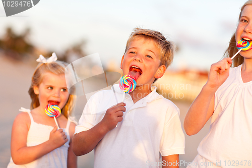 Image of Cute Brother and Sisters Enjoying Their Lollipops Outside