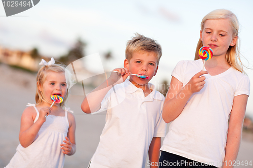 Image of Cute Brother and Sisters Enjoying Their Lollipops Outside
