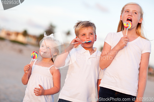 Image of Cute Brother and Sisters Enjoying Their Lollipops Outside