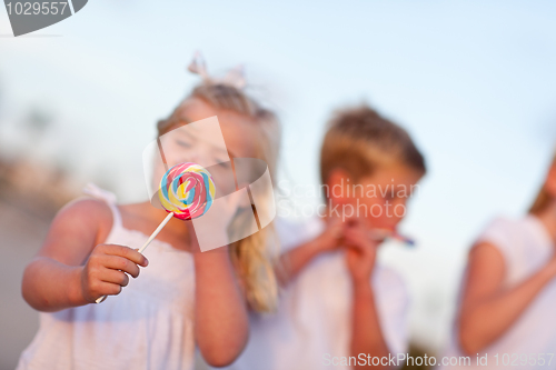 Image of Cute Brother and Sisters Enjoying Their Lollipops Outside