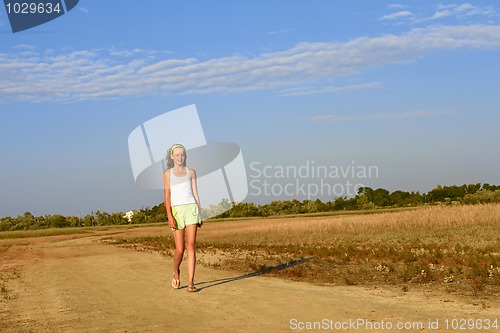 Image of Teenage girl walking on the sandy road