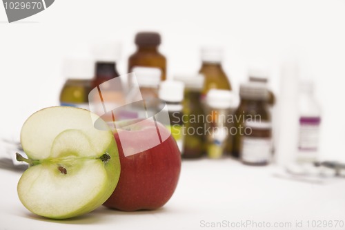 Image of green and red apples in front of many pills and pill