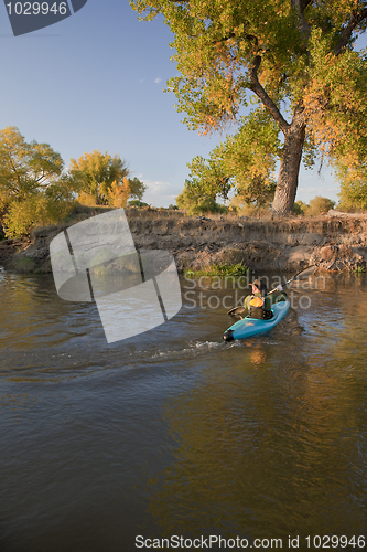 Image of kayaker paddling across a river