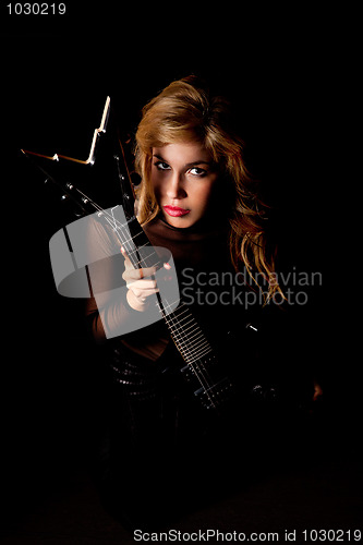 Image of beautiful young woman sitting with a electric guitar