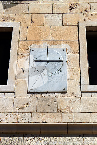 Image of marble sun-dial between two windows