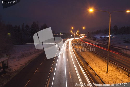 Image of In winter car lights in the night on the town road.