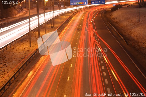 Image of Car lights in the night on the town highway in winter lamplight.