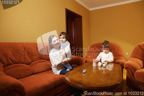 Image of Smiling mother with daughters at home