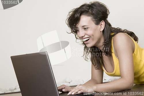 Image of laughing girl with the laptop lying on the floor
