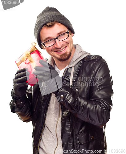 Image of Warmly Dressed Young Man Holding Wrapped Gift To His Ear