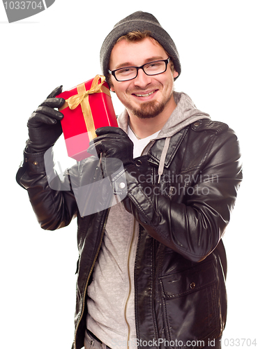 Image of Warmly Dressed Young Man Holding Wrapped Gift To His Ear