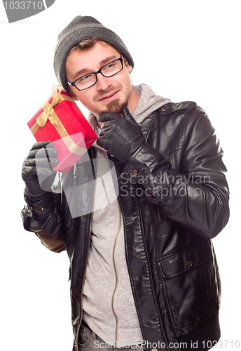 Image of Warmly Dressed Young Man Holding Wrapped Gift To His Ear