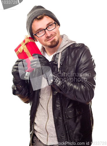 Image of Warmly Dressed Young Man Holding Wrapped Gift To His Ear