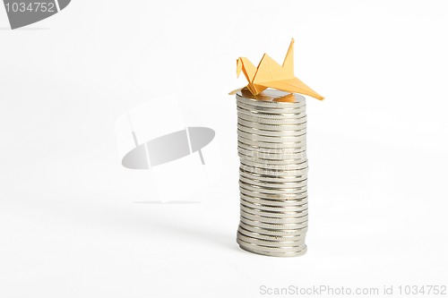 Image of stack of silver coins and yellow origami bird