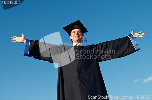 Image of graduate with open arms outdoors