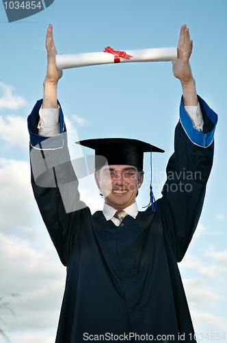 Image of graduate with diploma in hands over head