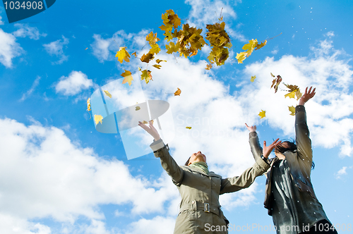 Image of Two girls and Autumn leaves over blue sky